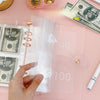 A hand is opening a clear pink envelope budget binder set for cash organization with US currency inside.