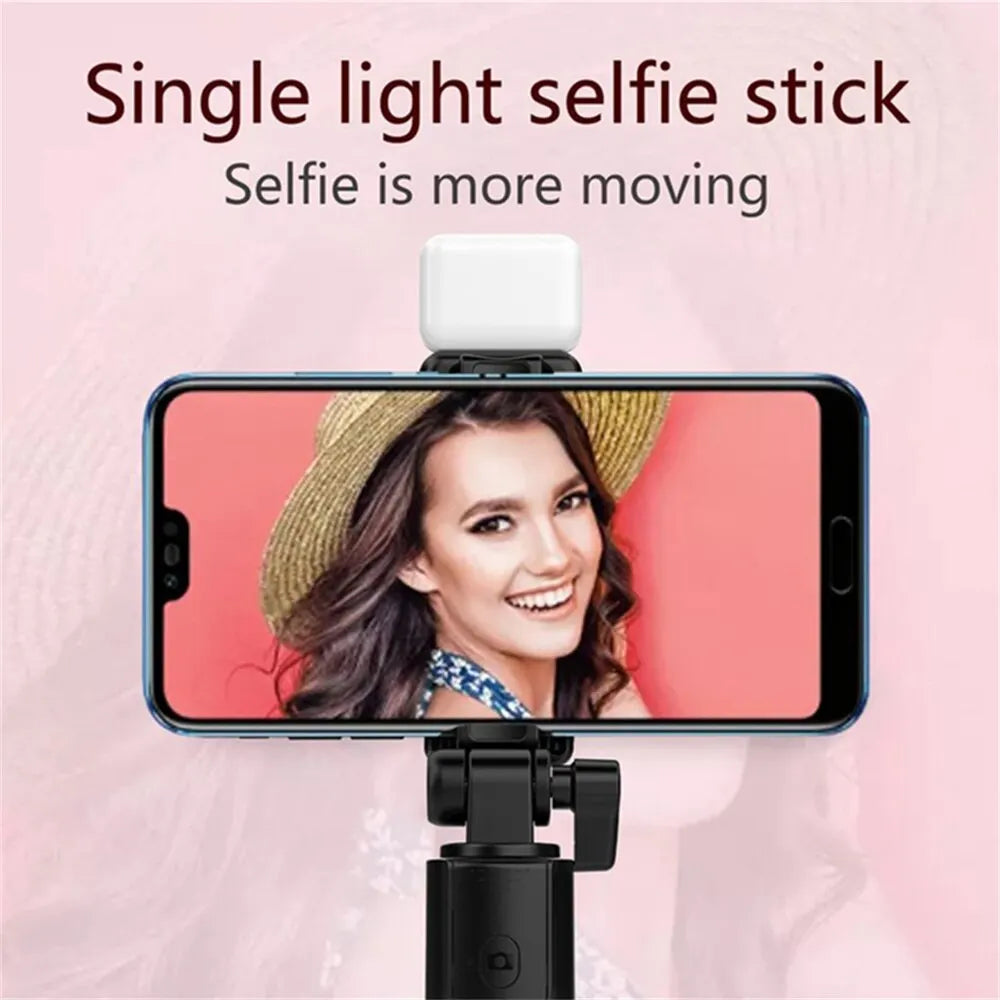 A smartphone is mounted on a selfie stick with a single light, showing a woman smiling.