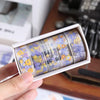 A set of decorative transparent washi tape rolls featuring floral patterns in purple, yellow, and white.