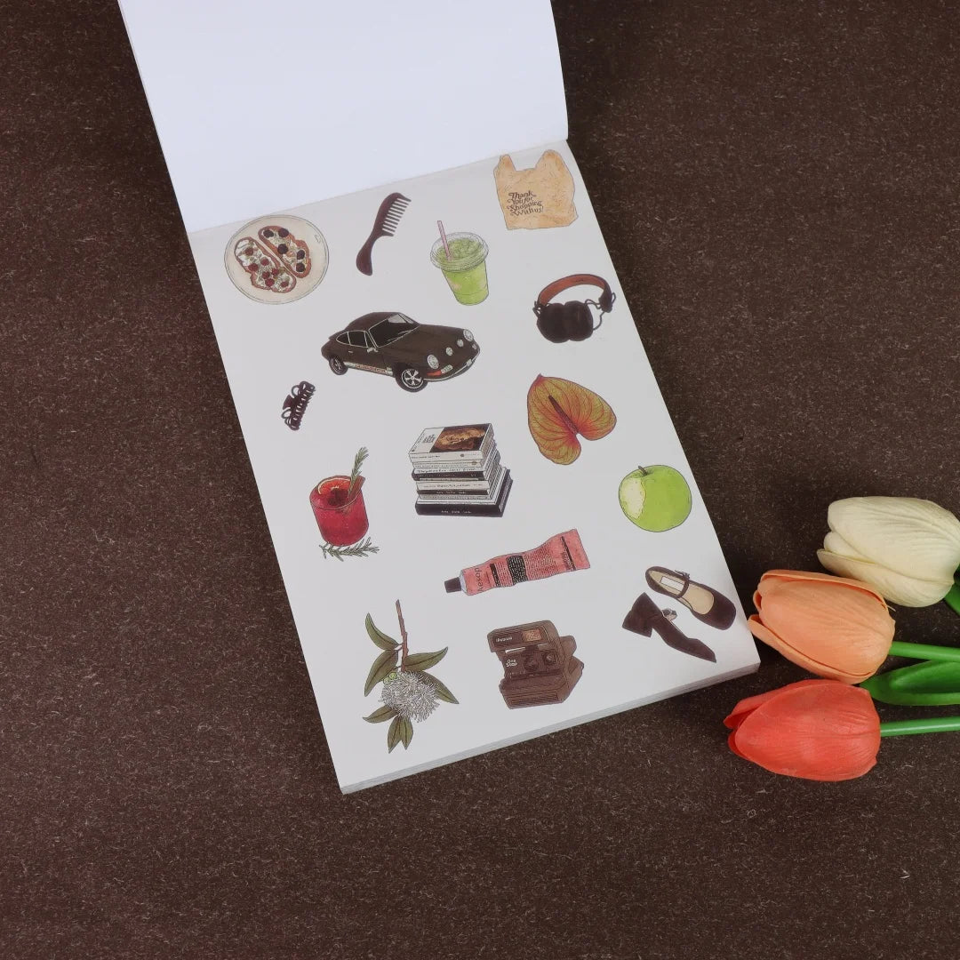 A white sticker book page featuring various fruit and accessory icons like a guitar, headphones, leather shoes, and various f