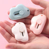 Two portable utility knives in light blue and pink are held in a person's hand.