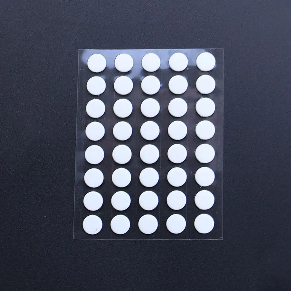 A clear plastic sheet containing 40 white adhesive glide feet for universal mouse skates.