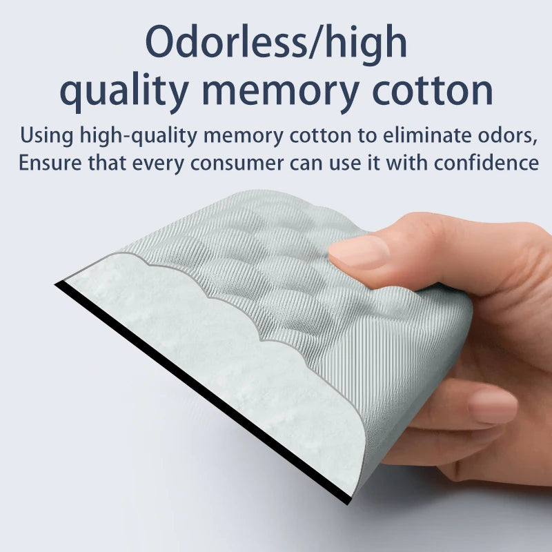 A hand holds a light green memory cotton wrist rest pad with a textured surface.