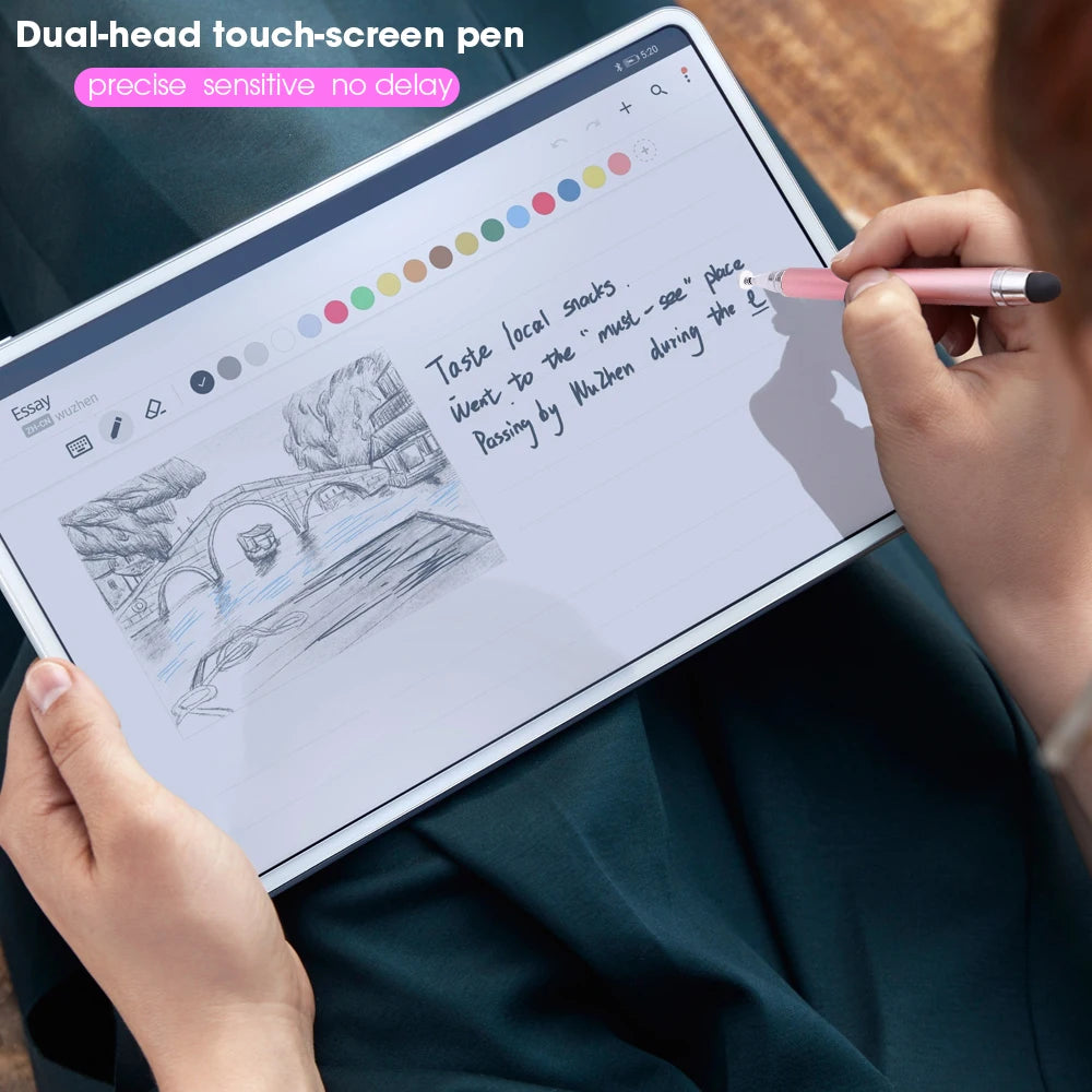 A hand holds a dual-head touch-screen pen writing on a tablet displaying text and drawings.