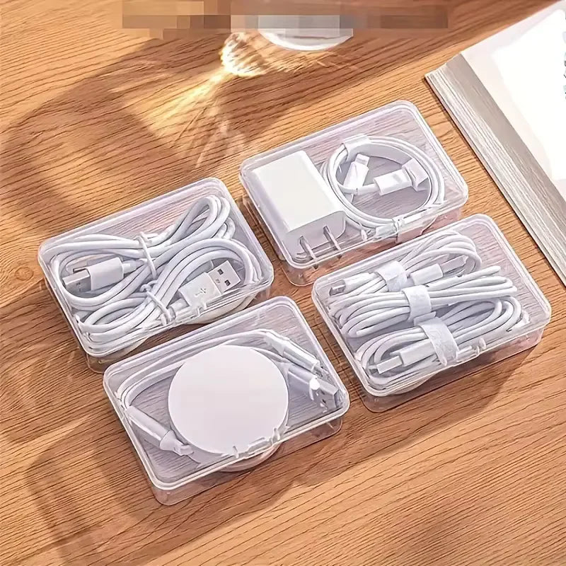Clear plastic storage boxes containing various electronic cables and connectors for desk or travel organization