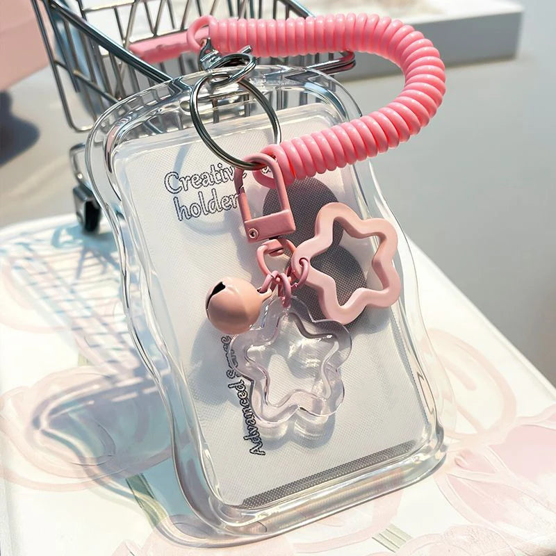 A clear card holder with a pink silicone keychain attached, displayed on a white surface.