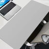 A large gray gaming mouse pad is shown next to a laptop and a desk setup.