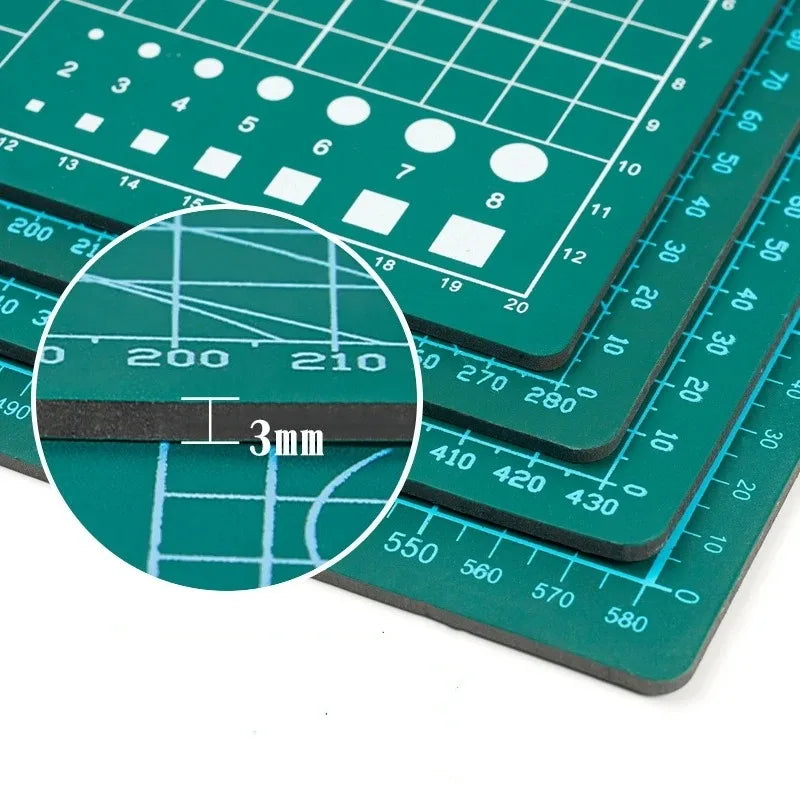 A close-up view of a green double-sided self-healing cutting mat with measurement lines and grid patterns.