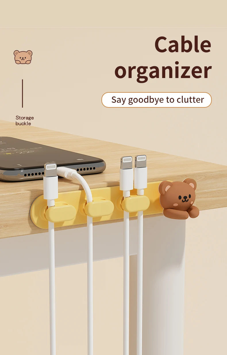 A yellow cable organizer with multiple white cables is shown on a wooden desk next to a laptop and a teddy bear.