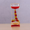 A glass hourglass filled with colored liquid, showing a slow flow of red and yellow liquids.