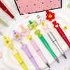 A set of colorful beaded ballpoint pens featuring pink, yellow, and green accents arranged on a white plate.