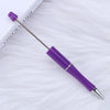 A purple DIY beadable pen with a silver tip rests on a white, fluffy surface.