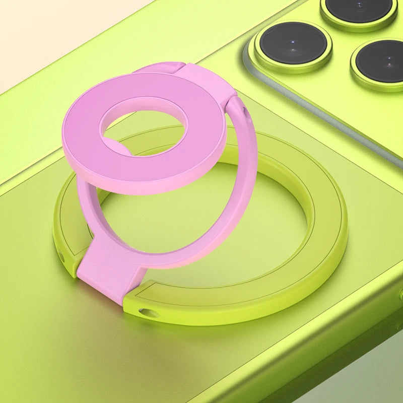 A pink phone ring holder stand is shown resting on a lime green surface next to a yellow charging pad.