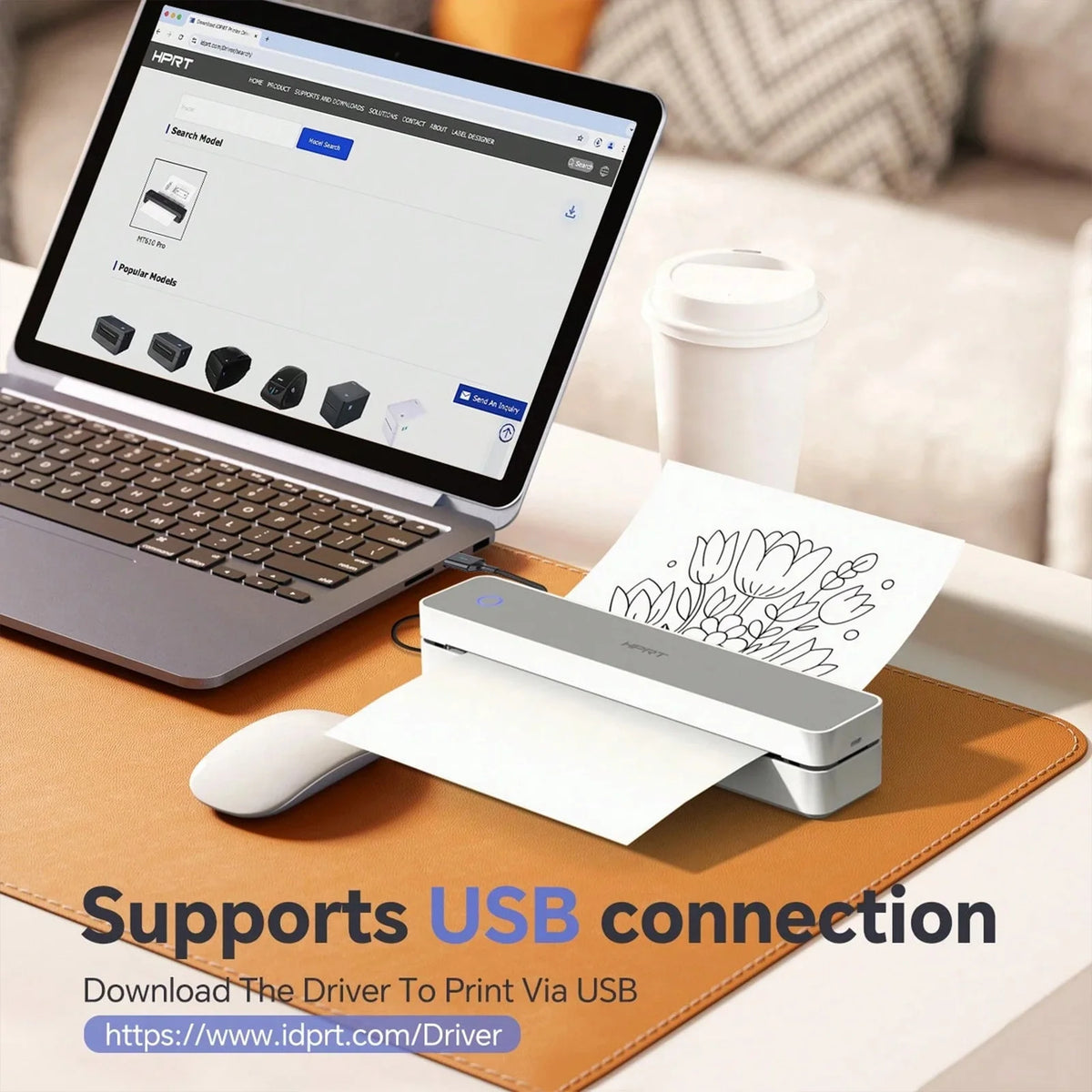 A compact thermal receipt printer and accessories are shown on a laptop and a brown pad.