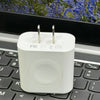 Chargeur multi-ports blanc 3-en-1 posé sur un clavier d'ordinateur portable noir.