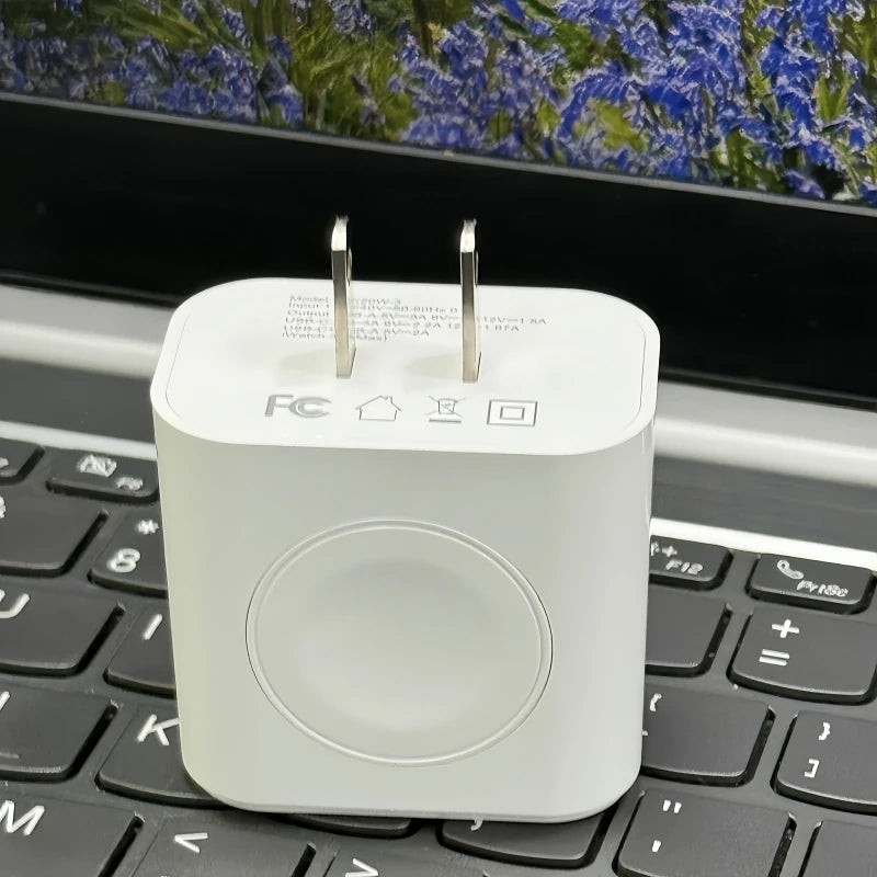 Chargeur multi-ports blanc 3-en-1 posé sur un clavier d'ordinateur portable noir.