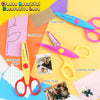 A collection of craft scissors, including pink, yellow, and purple, are displayed with various colored paper and photo materi