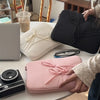 A collection of laptop sleeves, including a black padded sleeve and a pink padded sleeve, are displayed on a table.