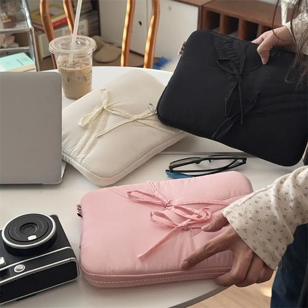 A collection of laptop sleeves, including a black padded sleeve and a pink padded sleeve, are displayed on a table.
