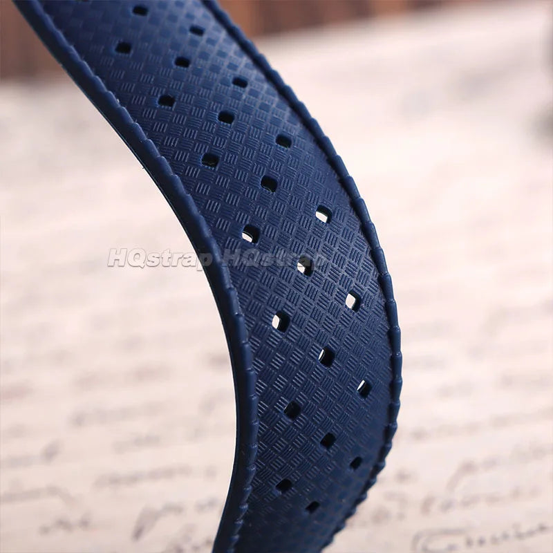 A close-up of a dark blue perforated silicone watch strap with a textured pattern.