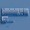 A collection of blue and white PBT keycaps for a mechanical keyboard shown from above.