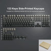 A set of 133 side-printed keycaps for mechanical keyboards shown next to a brass-colored keycap.