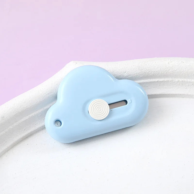 A light blue portable utility knife with a round button and blade visible on a white surface.