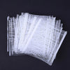 A bundle of white, thin, flexible plastic strips or tags laid out on a dark surface.