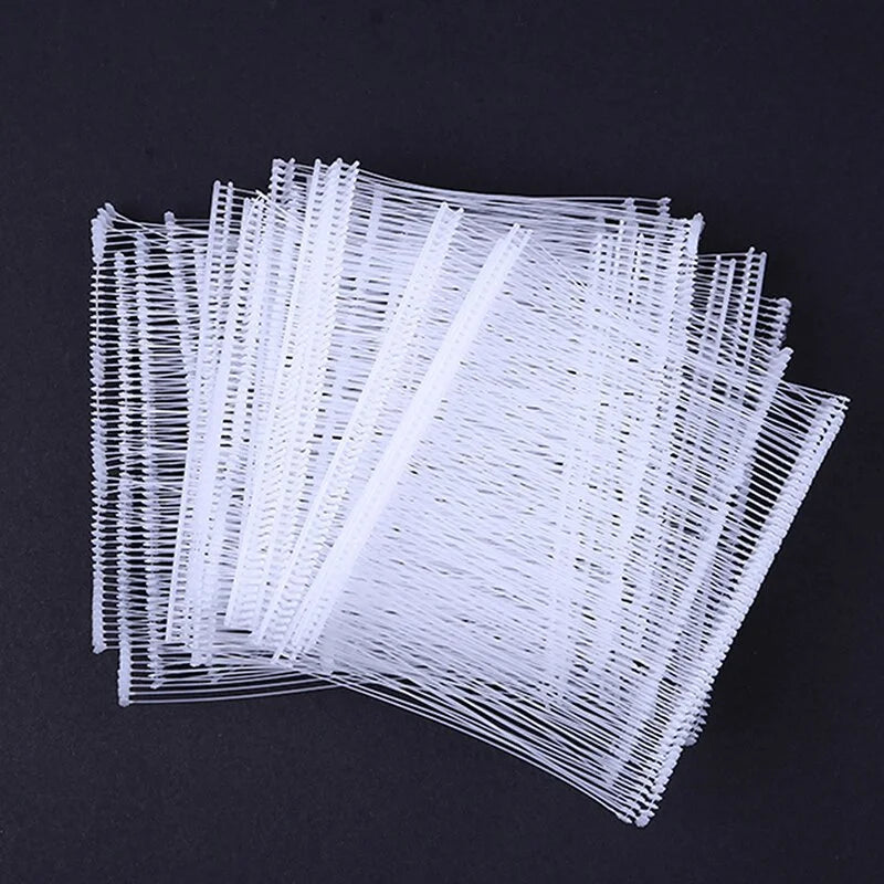 A bundle of white, thin, flexible plastic strips or tags laid out on a dark surface.