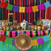 A colorful Día de Muertos papel picado banner displayed on a table with flowers and decorative elements.