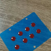 Blue acrylic mouse skates with red dots placed on a wooden surface.