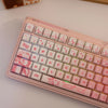 A close-up of a pink mechanical keyboard featuring PBT side-printed translucent keycaps with heart and ECG graphics.