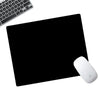 Eine weiße Apple-Maus liegt auf einer schwarzen Anti-Rutsch-Mauspad neben einer Computertastatur.