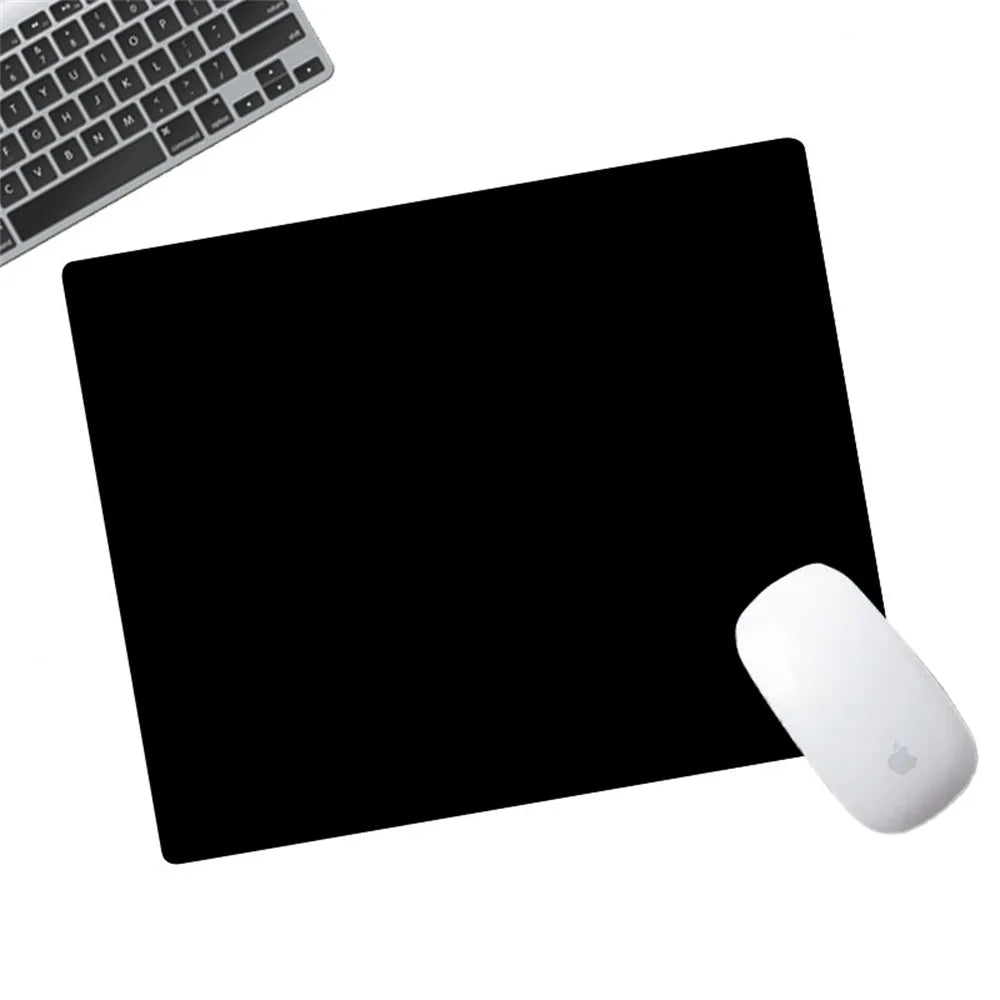 Eine weiße Apple-Maus liegt auf einer schwarzen Anti-Rutsch-Mauspad neben einer Computertastatur.
