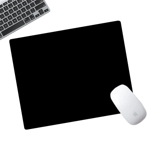 A white Apple mouse is placed on a black anti-slip mouse pad next to a computer keyboard.