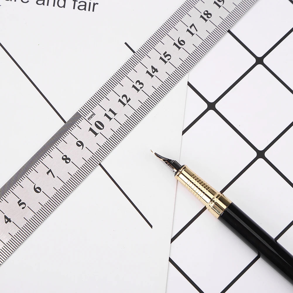 A black pen is placed next to a stainless steel measuring ruler marked in millimeters on white paper.