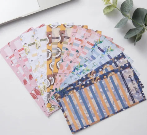 A stack of colorful A6 budget planner binders with envelope pockets and expense sheets