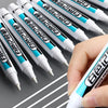 A hand holds a white permanent paint marker pen with blue accents, showing the tip and barrel.