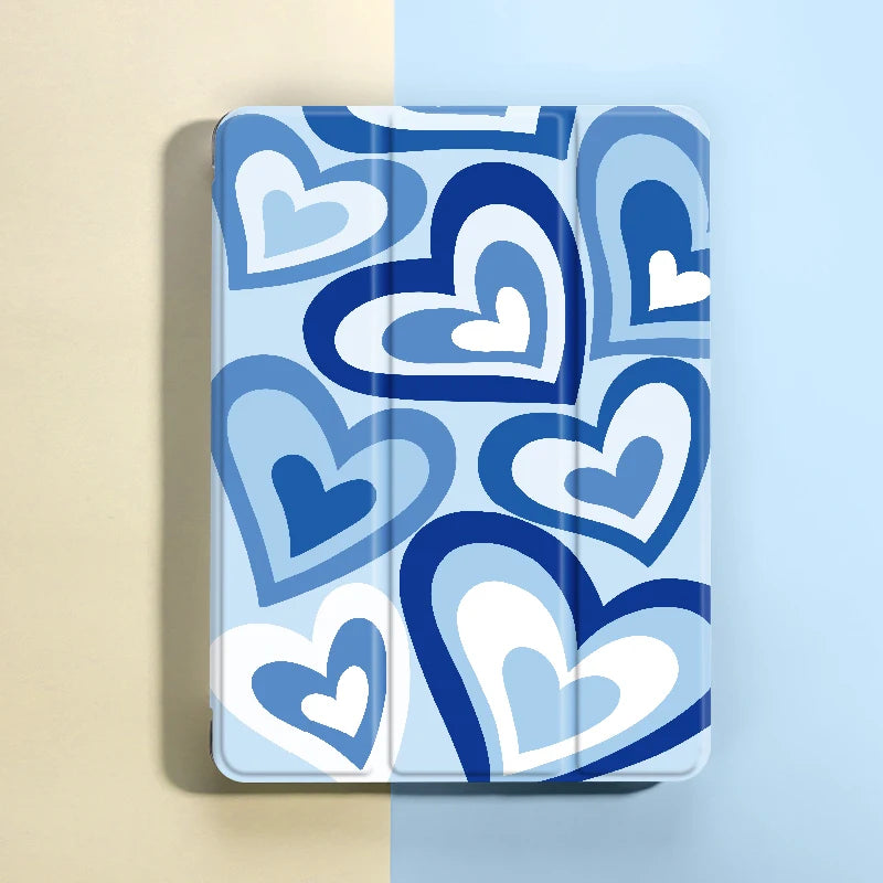 A blue heart pattern iPad case featuring white and light blue hearts, shown against a pale background.