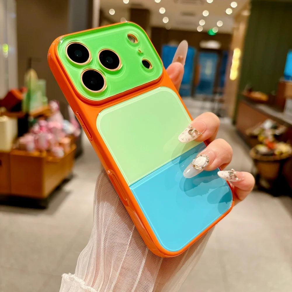 An orange acrylic phone case with green and blue colored blocks is held by a hand in a blurred indoor setting.