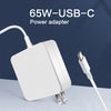 Adaptateur secteur USB-C blanc de 65W branché à un câble sur une surface gris clair.