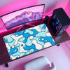 A blue and white wave pattern non-slip mouse pad is displayed on a wooden desk next to a computer monitor.