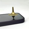 A brass metal hand spinning top fidget toy resting on a dark surface.
