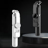 A white Bluetooth selfie stick with an LED fill light and tripod stand shown against a dark background.