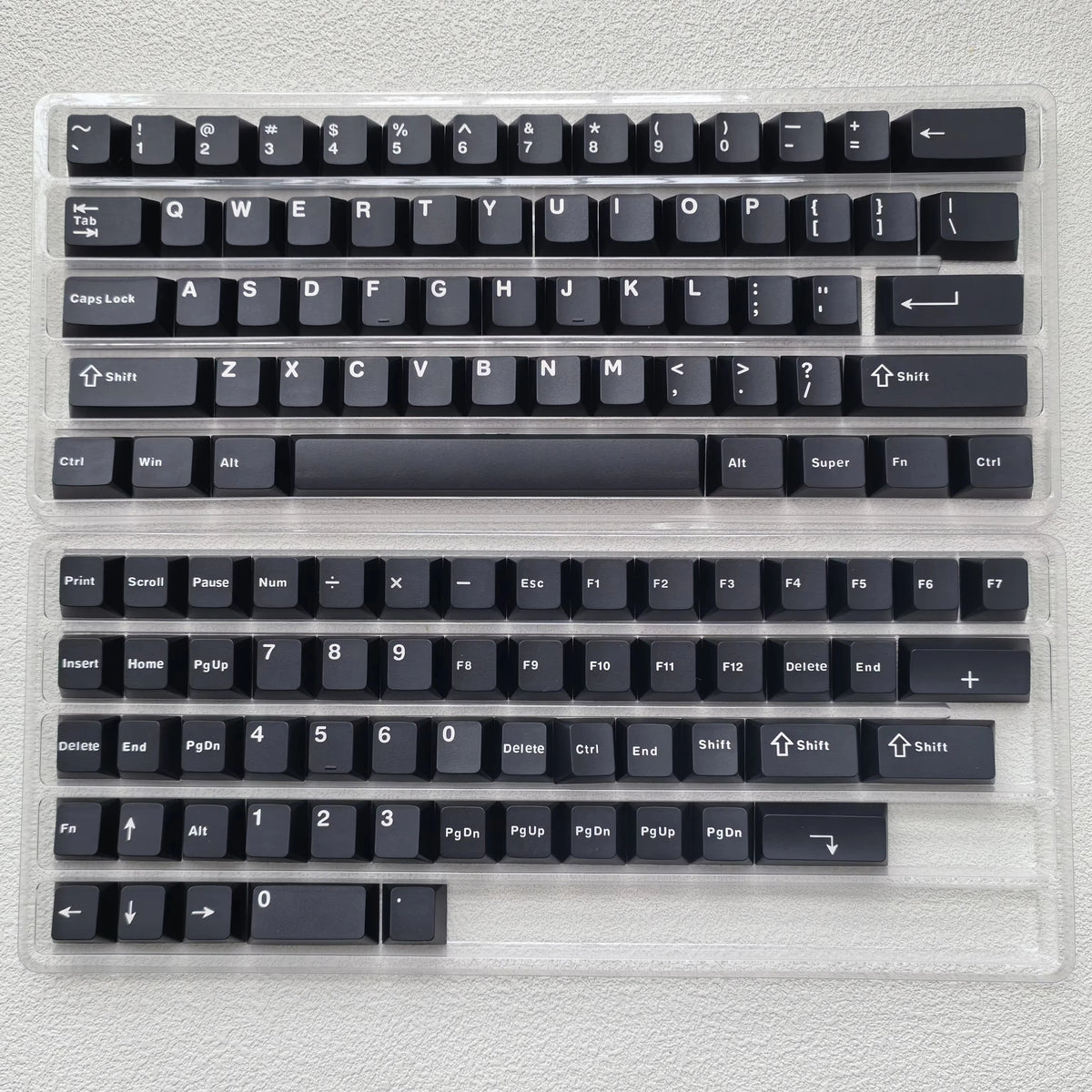 A clear plastic case containing a full set of dark blue PBT keycaps for a mechanical keyboard