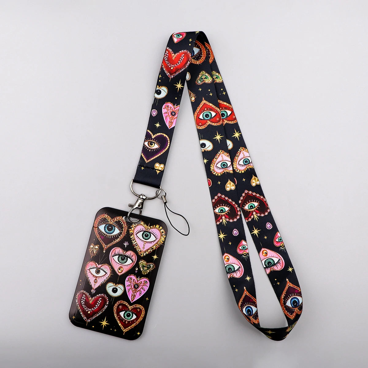 A black lanyard featuring a repeating pattern of colorful, heart-shaped eyes and designs for badges and keys.