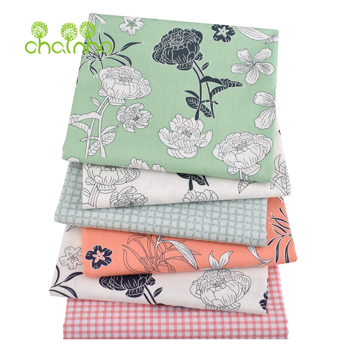 Gestapelte Twill-Baumwollstoffe mit floralen Mustern in Grün-, Weiß- und Orangetönen.