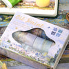A box of oil paint with a decorative wooden-look lid and an oval cutout showing the paint inside.
