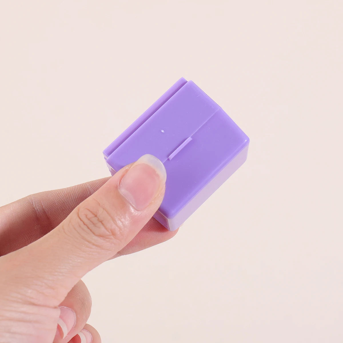 A hand holds a purple privacy protection roller stamp for confidential documents.