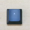 A close-up view of a blue replacement keycap with a triangular shape for a Dell Alienware keyboard.